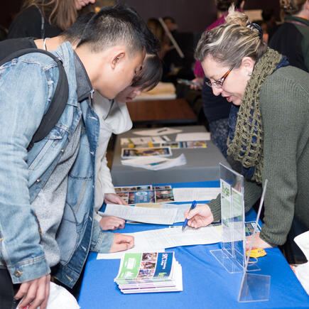 Students discuss future educational options with a faculty at a seminar booth.